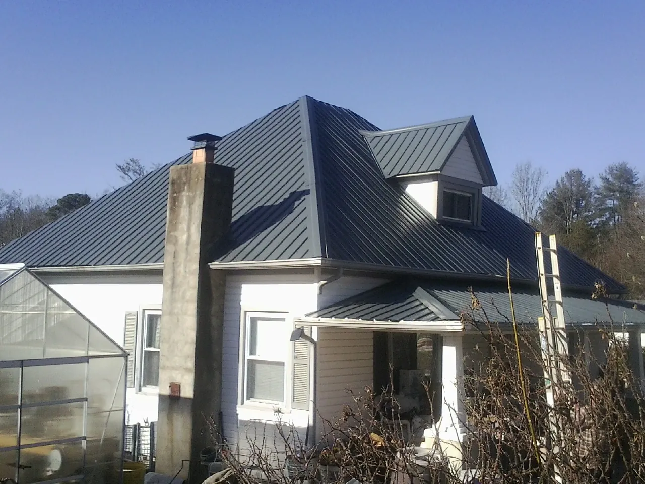 Dark blue standing seam metal roof on a white farmhouse with dormer — Slate & Tile Roof Repair by Roofing Brothers in Bainbridge Island