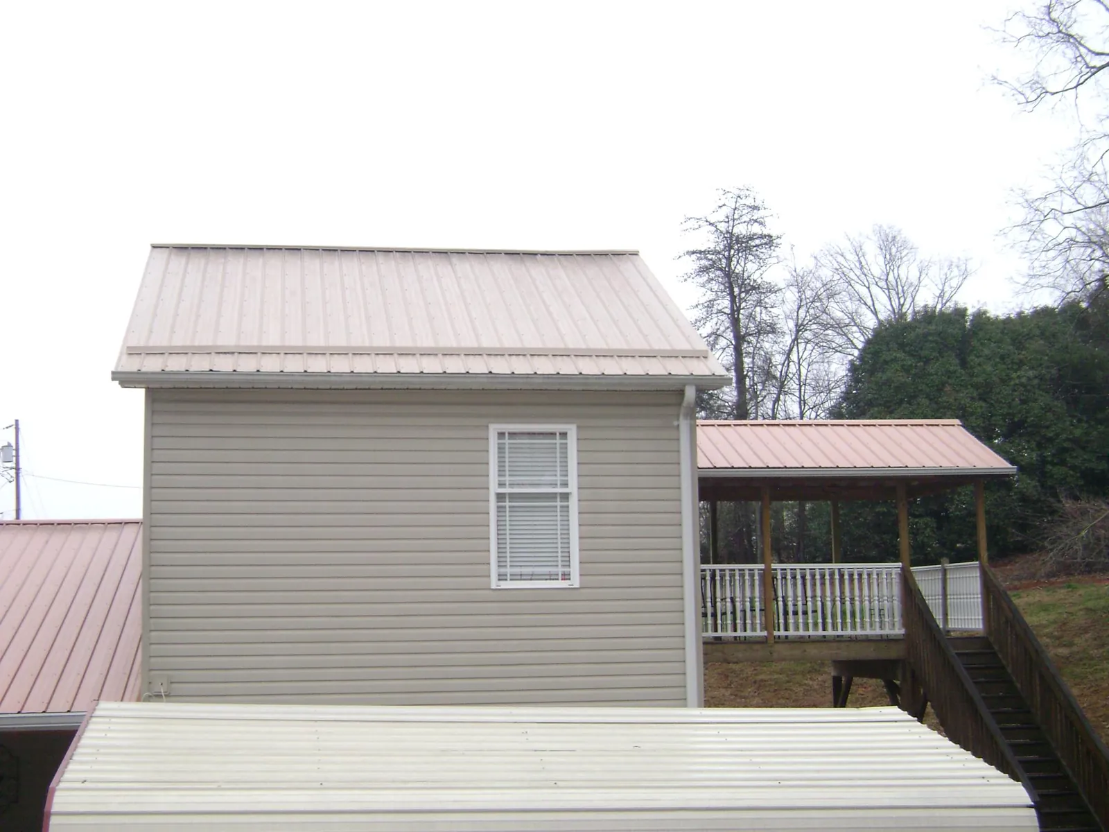 Tan metal roofs on a two story addition and attached porch, from a Roof Replacement job in Bainbridge Island