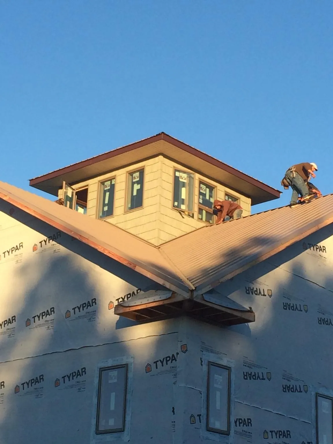 Roofers working around a rooftop cupola on a new metal roof at sunset — Roof Waterproofing in Bainbridge Island by Roofing Brothers